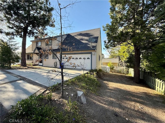 view of front facade with concrete driveway, fence, a chimney, and a garage
