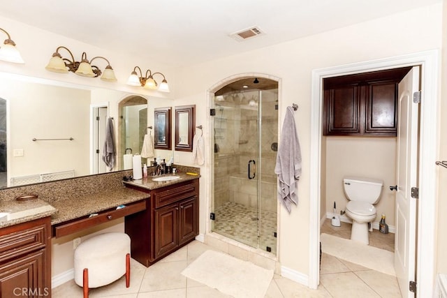 bathroom with toilet, vanity, tile patterned floors, and walk in shower