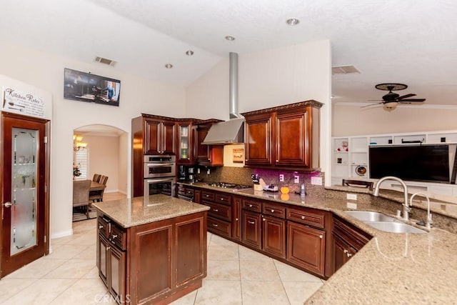 kitchen with backsplash, vaulted ceiling, ceiling fan with notable chandelier, light stone counters, and sink