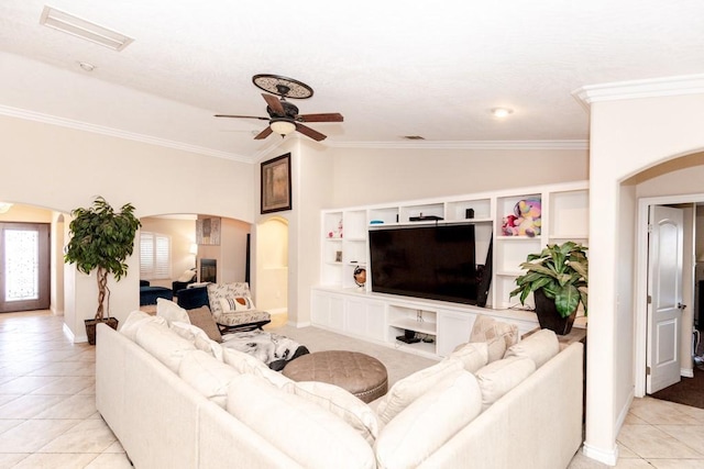 tiled living room featuring ceiling fan, ornamental molding, and lofted ceiling