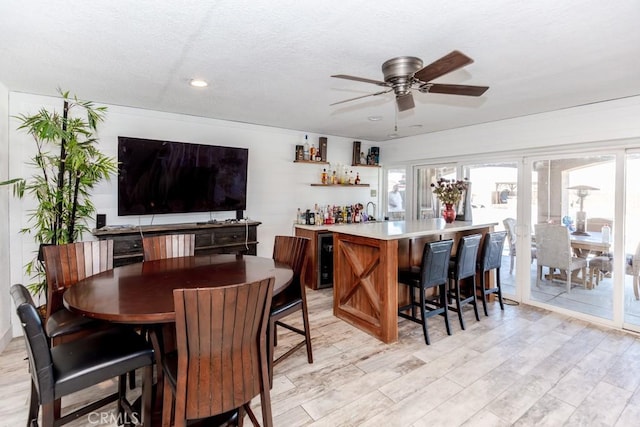 bar with light wood-type flooring and ceiling fan