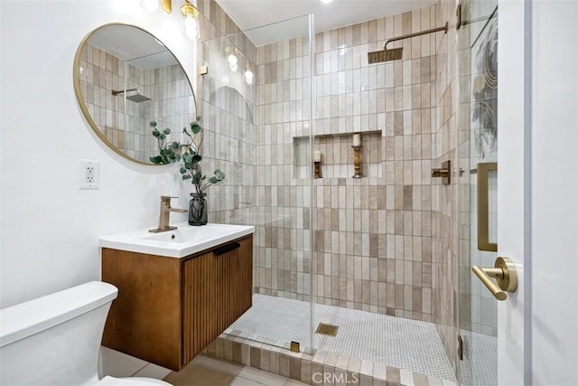 bathroom featuring a shower with shower door, vanity, tile patterned floors, and toilet