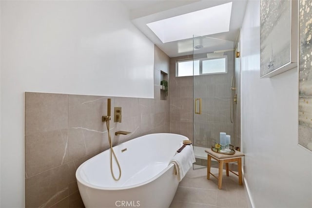 bathroom with tile walls, tile patterned floors, a skylight, and plus walk in shower