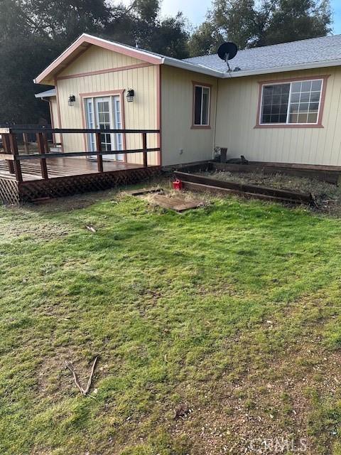 back of house with a deck and a yard