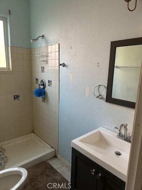 bathroom with vanity, toilet, tile patterned floors, and tiled shower