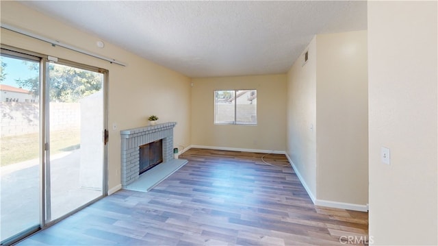 unfurnished living room featuring a textured ceiling, a fireplace, and light hardwood / wood-style floors