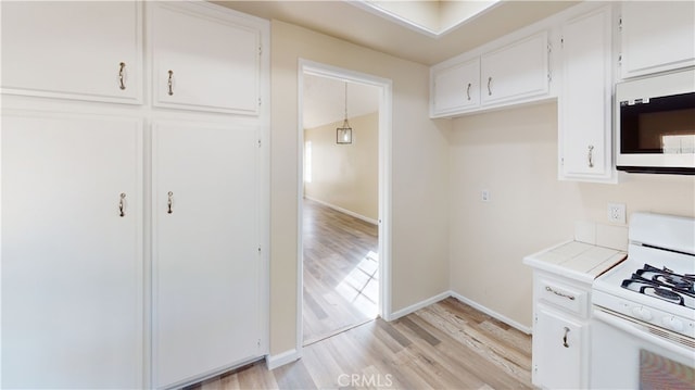 kitchen featuring pendant lighting, white appliances, light hardwood / wood-style flooring, and white cabinets