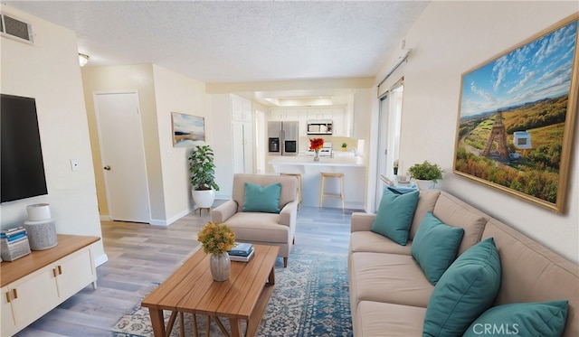 living room featuring a textured ceiling and light hardwood / wood-style floors