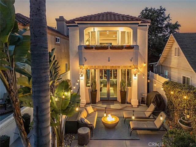 back house at dusk featuring french doors and a patio