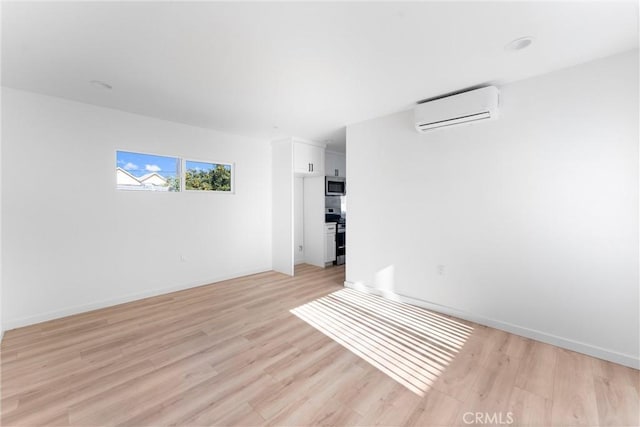 spare room featuring light wood-type flooring and an AC wall unit