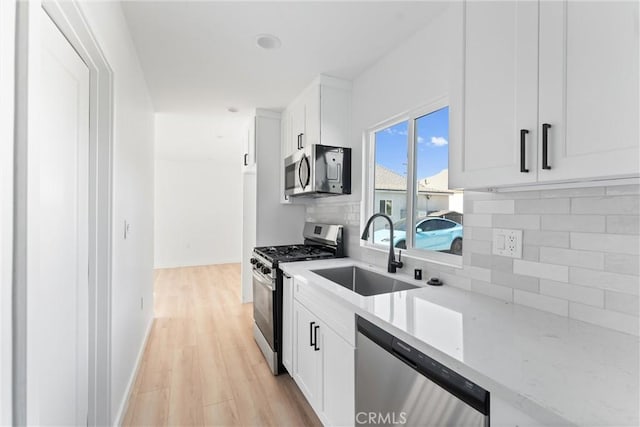 kitchen with white cabinets, decorative backsplash, sink, and stainless steel appliances