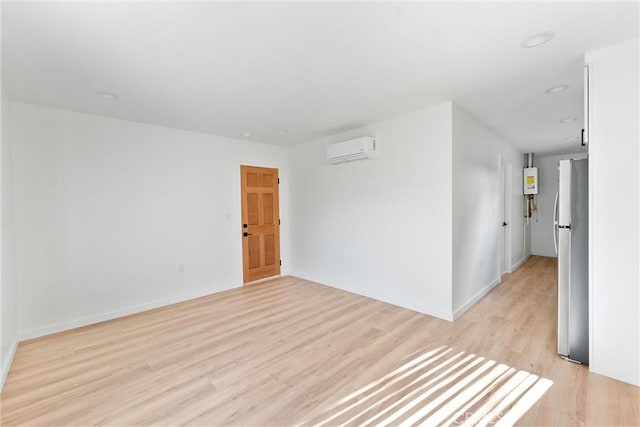 unfurnished room with light hardwood / wood-style flooring and a wall unit AC