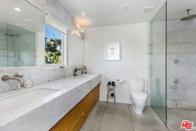 bathroom with toilet, tile patterned floors, and tiled shower