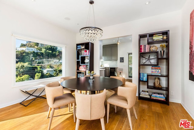 dining room with light wood-type flooring and an inviting chandelier