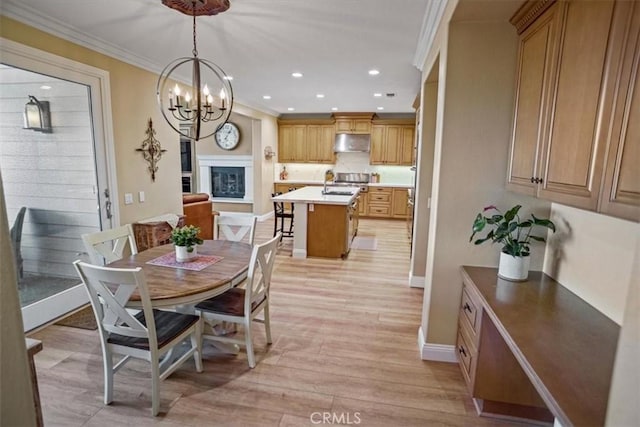 dining area featuring light wood-type flooring, an inviting chandelier, and crown molding