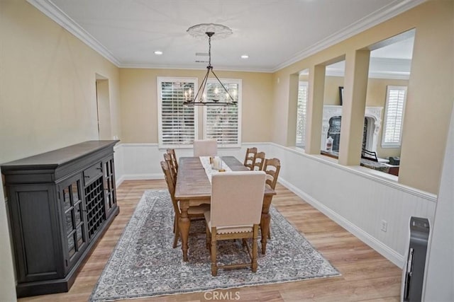 dining space with a notable chandelier, light hardwood / wood-style floors, and crown molding