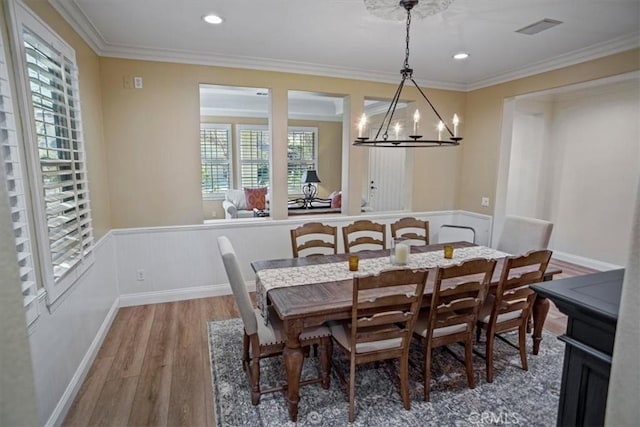 dining space featuring wood-type flooring, an inviting chandelier, and ornamental molding