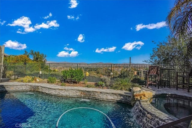 view of swimming pool featuring pool water feature and an in ground hot tub