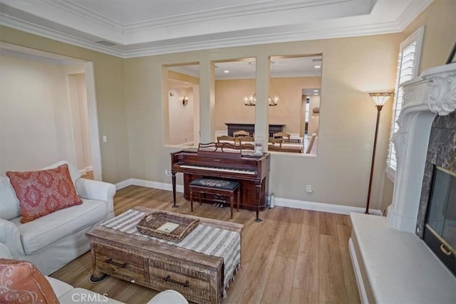 living room with a premium fireplace, a chandelier, ornamental molding, and light hardwood / wood-style flooring