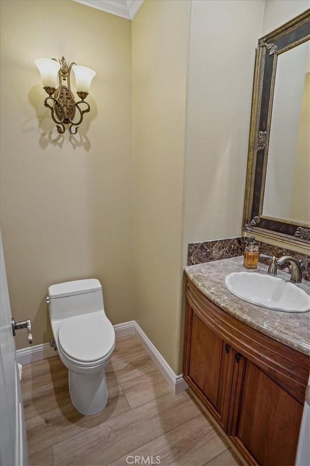 bathroom with hardwood / wood-style floors, toilet, ornamental molding, and vanity