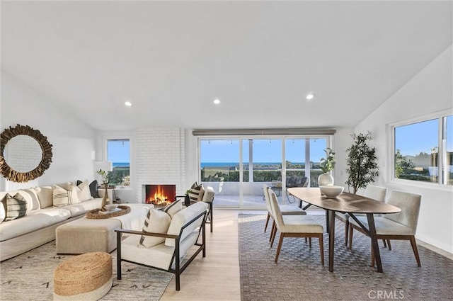 living room with light hardwood / wood-style floors, vaulted ceiling, and a fireplace