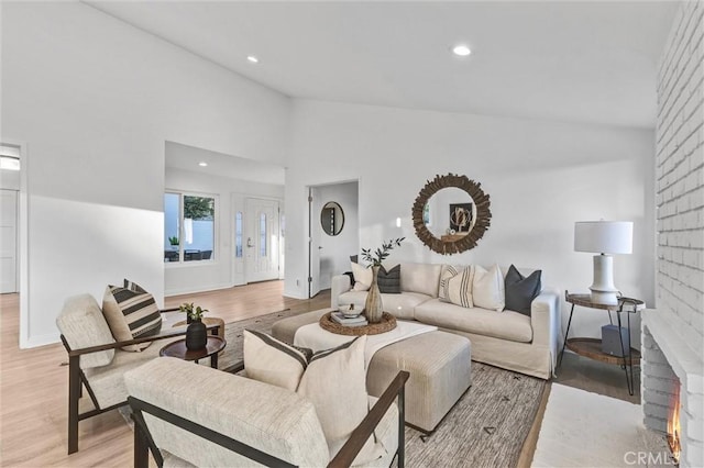 living room with light hardwood / wood-style flooring, lofted ceiling, and a fireplace