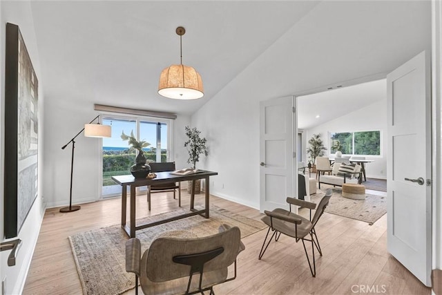 home office with high vaulted ceiling, plenty of natural light, and light hardwood / wood-style flooring