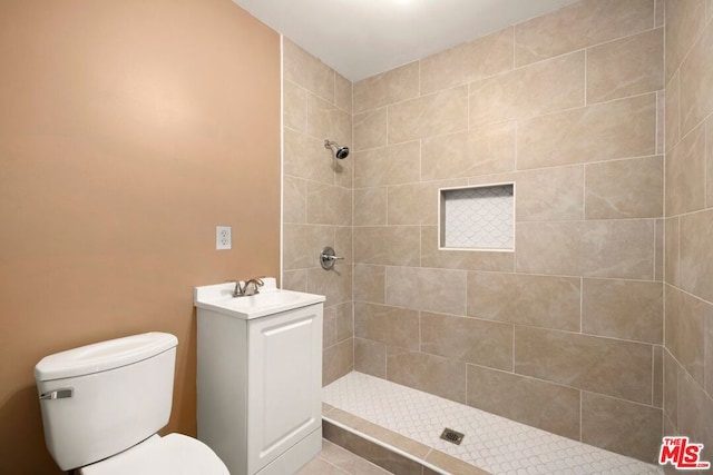 bathroom with toilet, vanity, and a tile shower