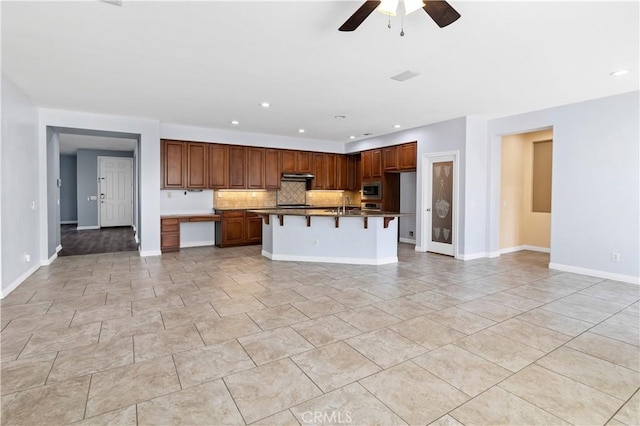 kitchen featuring stainless steel microwave, open floor plan, under cabinet range hood, and a sink