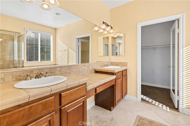 full bathroom with a sink, a spacious closet, a shower stall, and tile patterned flooring