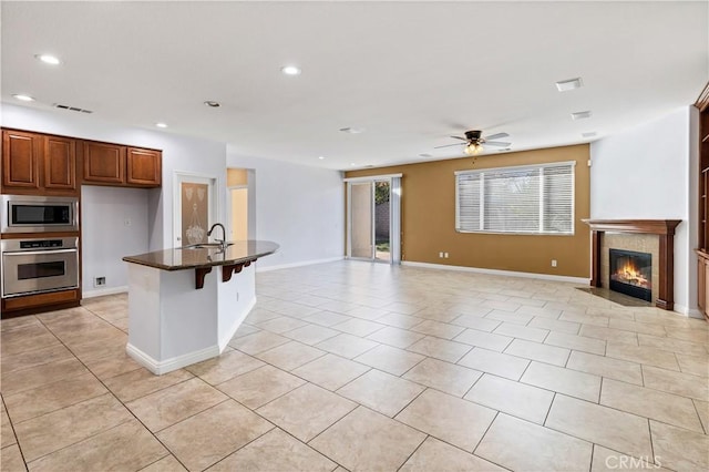 kitchen with open floor plan, a fireplace with flush hearth, light tile patterned floors, recessed lighting, and stainless steel appliances