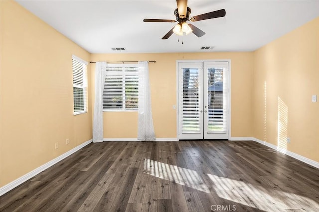 unfurnished room featuring dark wood finished floors, plenty of natural light, baseboards, and visible vents