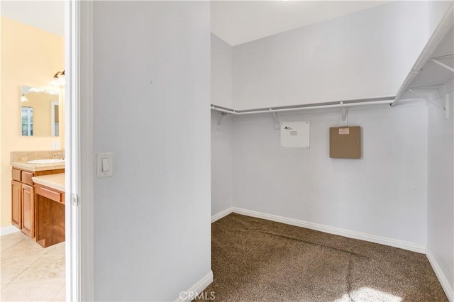 walk in closet with a sink, light colored carpet, and light tile patterned floors