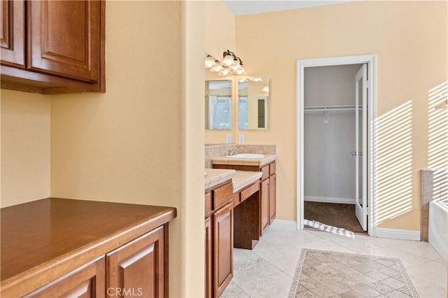 bathroom with a garden tub, vanity, tile patterned flooring, baseboards, and a spacious closet