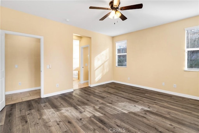 empty room featuring a ceiling fan, dark wood-type flooring, and baseboards