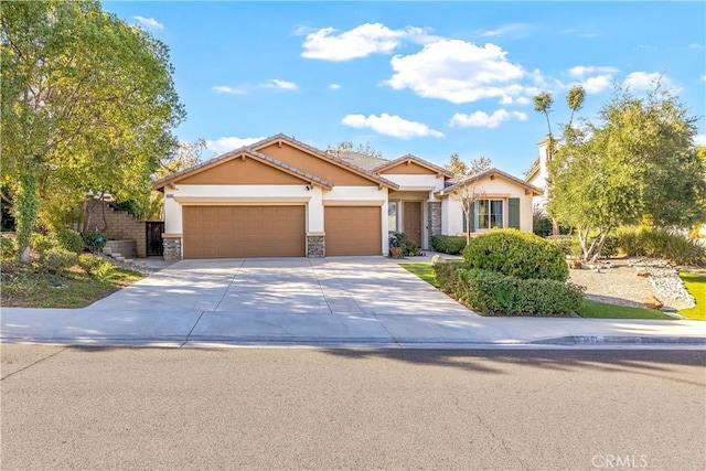 view of front of property featuring stucco siding, a tile roof, stone siding, concrete driveway, and an attached garage