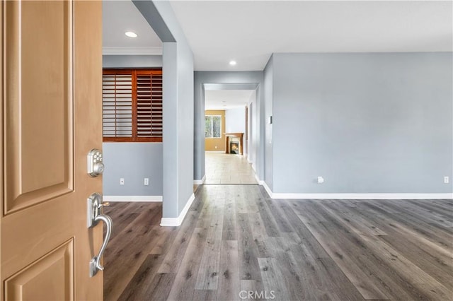 entryway featuring a lit fireplace, recessed lighting, baseboards, and wood finished floors