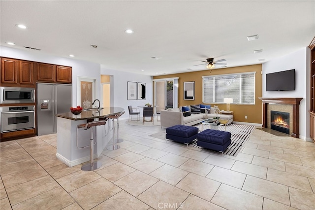 living area featuring light tile patterned floors, baseboards, a fireplace with flush hearth, recessed lighting, and ceiling fan