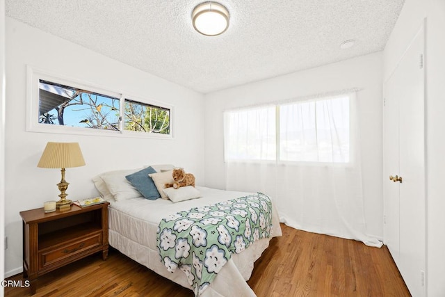 bedroom with a textured ceiling and wood-type flooring