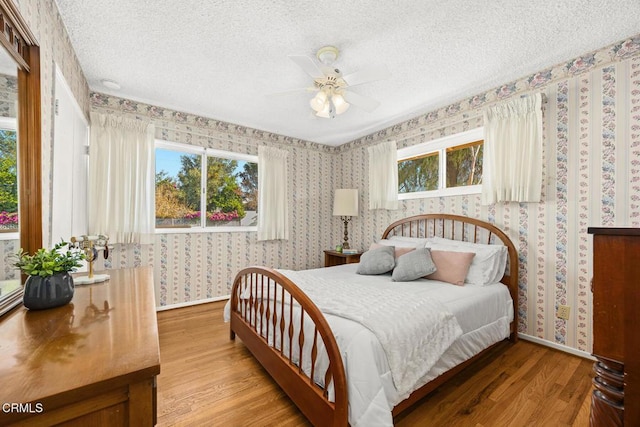 bedroom featuring ceiling fan, wood-type flooring, and a textured ceiling