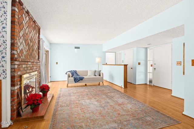 living room featuring wood-type flooring, a fireplace, and a textured ceiling