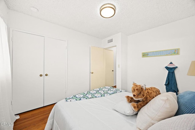 bedroom with a closet, a textured ceiling, and hardwood / wood-style floors