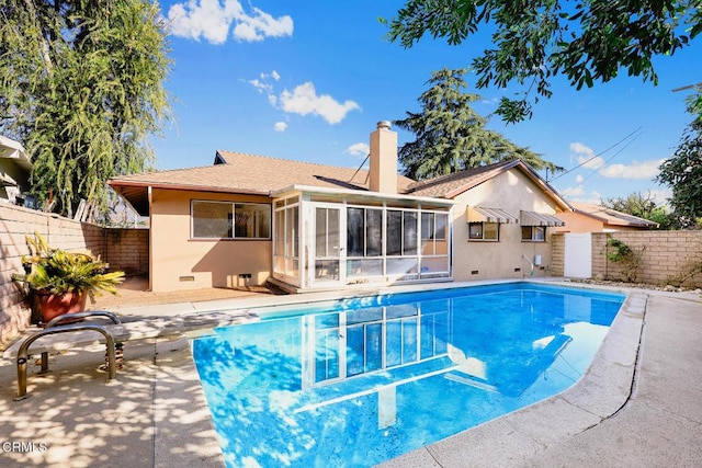 view of swimming pool featuring a patio area, a sunroom, and a diving board