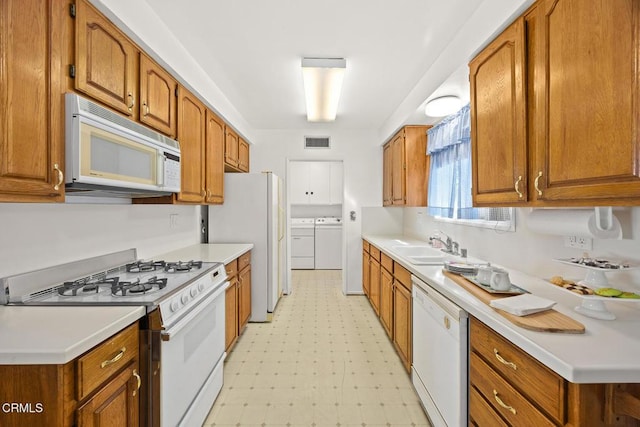 kitchen with sink, washing machine and clothes dryer, and white appliances