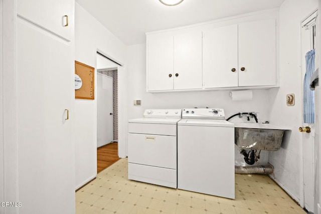 laundry room featuring cabinets, independent washer and dryer, and sink