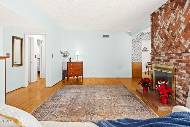 living room with a textured ceiling, a brick fireplace, and hardwood / wood-style flooring