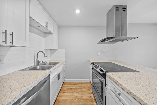 kitchen featuring island range hood, appliances with stainless steel finishes, decorative backsplash, white cabinets, and sink