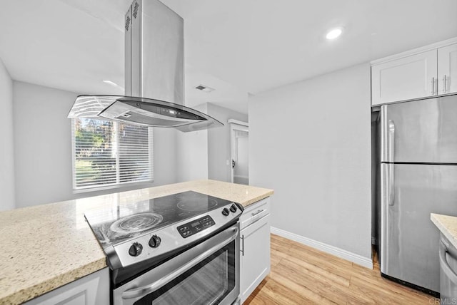 kitchen featuring island exhaust hood, light wood-type flooring, light stone countertops, appliances with stainless steel finishes, and white cabinets