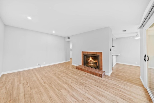 unfurnished living room featuring light hardwood / wood-style floors, ceiling fan, and a fireplace