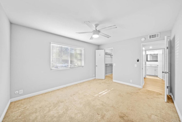 unfurnished bedroom featuring a spacious closet, ceiling fan, a closet, and light carpet